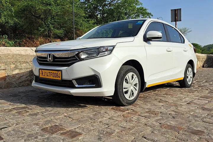 A white Honda car parked on a stone path.