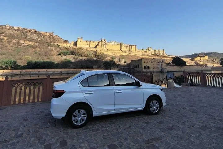 A white car parked with a fort in the background.